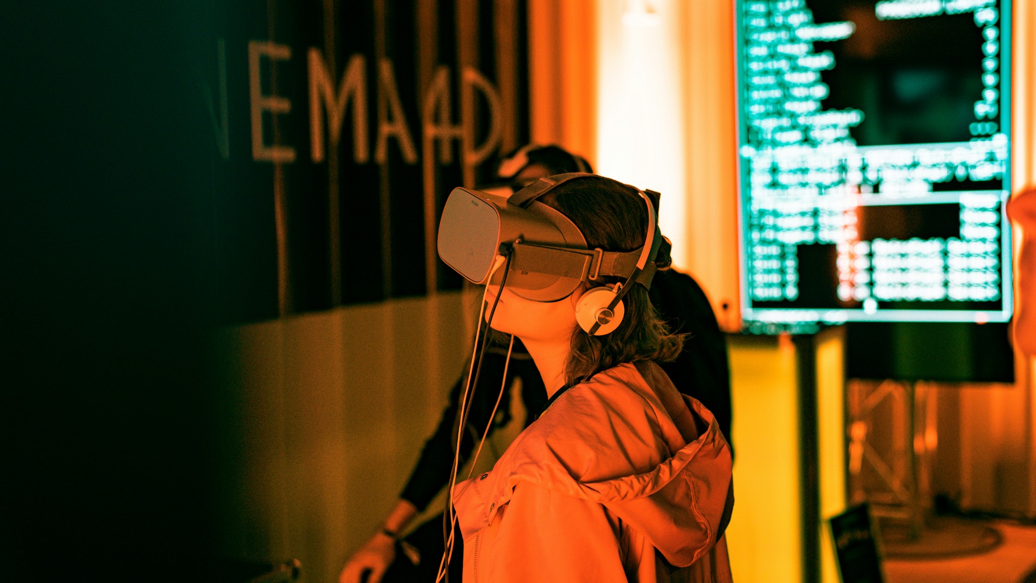 Person wearing a virtual reality headset and headphones in a warmly lit exhibition space